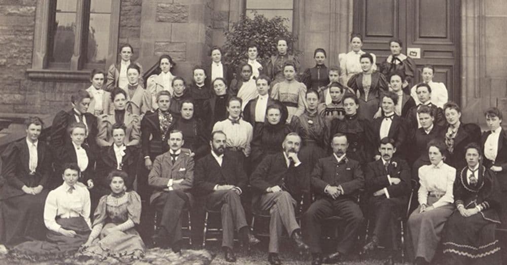 Fotografia de grupo de dezenas de estudantes de medicina, a maioria mulheres de pé, com professores sentados na fileira da frente.